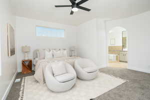 Bedroom with light colored carpet, arched walkways, ceiling fan, and ensuite bathroom