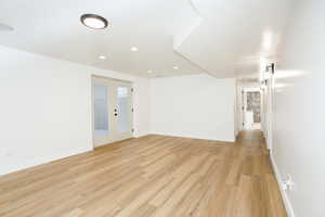Unfurnished room featuring french doors, light wood finished floors, and recessed lighting