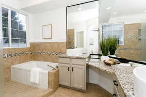 Bathroom with two vanities, a bath, light tile patterned floors, tile walls, and a shower stall