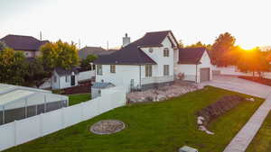 Back of property featuring stucco siding, concrete driveway, a fenced backyard, a garage, and a chimney
