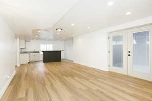 Unfurnished living room featuring recessed lighting, light wood finished floors, and french doors