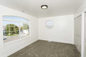 Spare room featuring dark carpet and baseboards