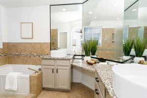 Bathroom with two vanities, a bath, a walk in shower, light tile patterned floors, and recessed lighting
