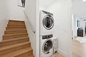 Laundry area featuring stacked washer and dryer. Staircase between the first and second levels.