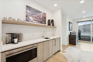 Wet bar featuring modern cabinets, open shelves, Wolf microwave and refrigerator.