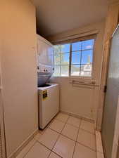 Laundry area with stacked washer / dryer and light tile patterned floors