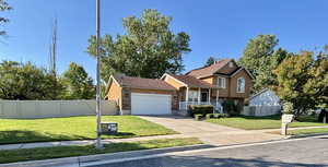 Tri-level home featuring an attached garage, concrete driveway, stucco siding, and covered porch