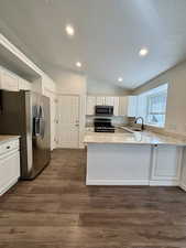 Kitchen featuring vaulted ceiling, light stone counters, a textured ceiling, appliances with stainless steel finishes, and recessed lighting