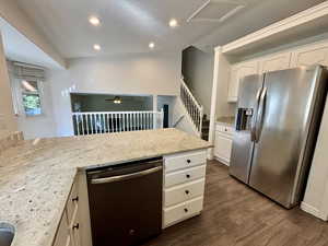 Kitchen with stainless steel appliances, recessed lighting, light stone countertops, white cabinets, and a peninsula