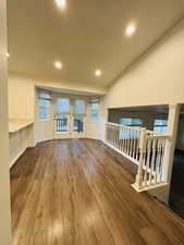 Unfurnished living room featuring hardwood / wood-style flooring, recessed lighting, healthy amount of natural light, and vaulted ceiling