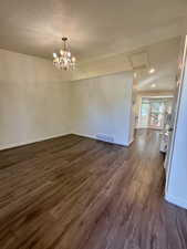 Spare room featuring dark wood-style floors, attic access, a chandelier, a textured ceiling, and recessed lighting