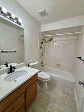 Bathroom with shower / bath combination, vanity, a textured ceiling, and wood tiled floors