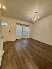 Foyer with dark wood-style floors, a textured ceiling, and a chandelier