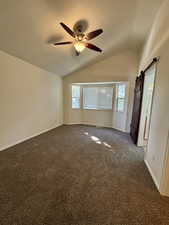 Master carpeted empty room featuring plenty of natural light, lofted ceiling, a barn door, a textured ceiling, and ceiling fan