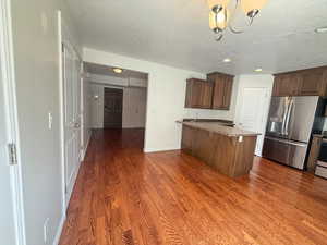 Kitchen with appliances with stainless steel finishes, dark wood finished floors, a breakfast bar, a peninsula, and a textured ceiling