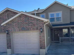 View of front facade with brick siding, stucco siding, a garage, and driveway
