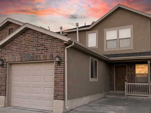 View of front facade with brick siding, stucco siding, and an attached garage