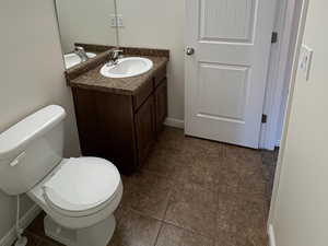 Full Hallway Bathroom featuring a textured ceiling, vanity, and dark tile patterned flooring