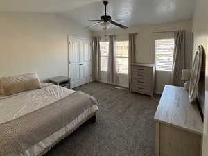 Main primary bedroom featuring vaulted ceiling, ceiling fan, and a textured ceiling