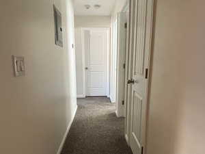 Hall featuring dark colored carpet