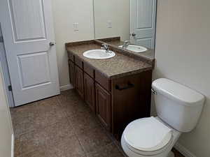 Primary bedroom bathroom with vanity, a textured ceiling, and dark tile patterned flooring