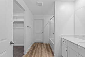 Full bath featuring vanity, bathing tub / shower combination, a spacious closet, and dark wood-style floors