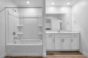 Bathroom with light wood-type flooring, washtub / shower combination, vanity, a closet, and recessed lighting