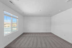 Carpeted spare room featuring baseboards and a textured ceiling