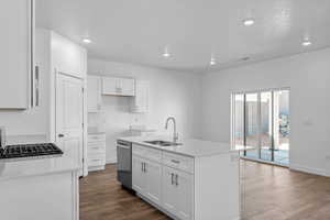 Kitchen with light stone countertops, recessed lighting, dark wood-style flooring, an island with sink, and stainless steel dishwasher