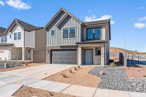 View of front of home with stone siding, an attached garage, driveway, board and batten siding, and covered porch