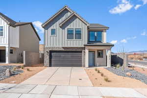 View of front of property featuring stone siding, an attached garage, concrete driveway, and board and batten siding