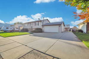 Bi-level home featuring a front lawn, concrete driveway, and a garage