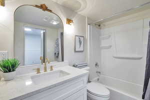 Full bath featuring shower / bathtub combination with curtain, vanity, and a textured ceiling