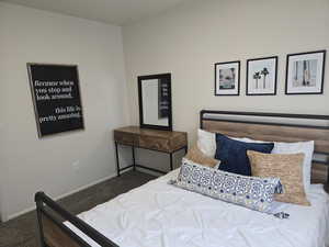 Bedroom featuring dark carpet and baseboards