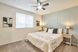 Bedroom with carpet flooring, a ceiling fan, and a decorative wall