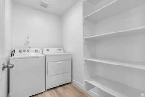 Laundry area with light wood-type flooring and separate washer and dryer