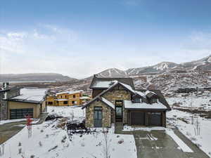 View of front of property with stone siding, driveway, and a mountain view