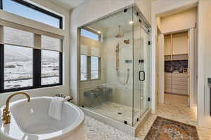 Full bath featuring a shower stall, a soaking tub, and a spacious closet