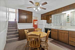 Kitchen with light countertops, white appliances, ceiling fan, and light colored carpet