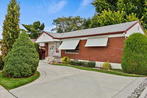 Ranch-style house featuring brick siding, a shingled roof, and concrete driveway