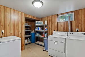 Laundry room featuring wood walls and washing machine and clothes dryer