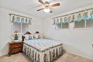 Carpeted bedroom with a ceiling fan and baseboards