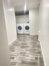 Washroom with wood finished floors and washer and dryer