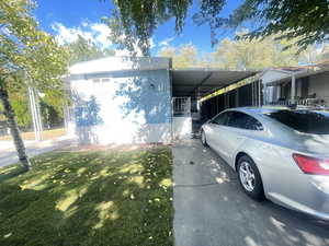 View of side of home featuring a yard, an attached carport, and driveway