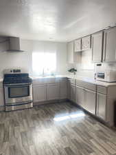 Kitchen featuring gray cabinets, gas range, a textured ceiling, dark wood-style floors, and light countertops