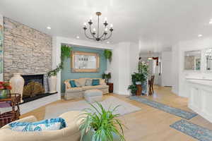 Living room with a chandelier, wood finished floors, a fireplace, and recessed lighting