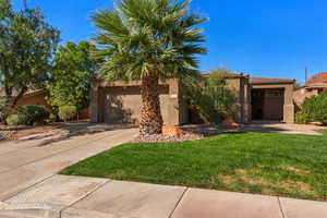 View of front of home featuring stucco siding, driveway, and a front yard