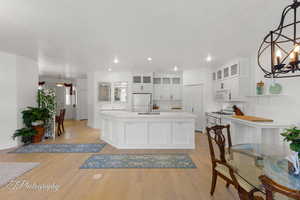 Kitchen with pendant lighting, glass insert cabinets, a chandelier, white appliances, and white cabinets