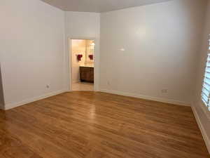 Unfurnished bedroom featuring dark wood-style floors and ensuite bath