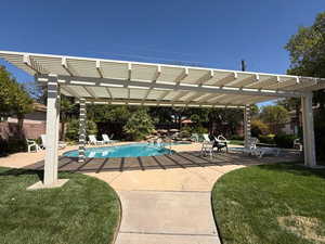 Swimming pool featuring a pergola, a patio area, and a lawn